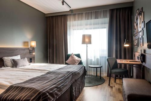 a hotel room with a bed and a desk and a window at Scandic Infra City in Upplands-Väsby