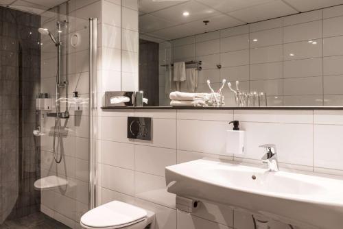 a bathroom with a sink and a toilet and a mirror at Scandic Infra City in Upplands-Väsby