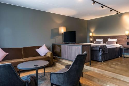 a hotel room with a bed and a couch and a tv at Scandic Infra City in Upplands-Väsby