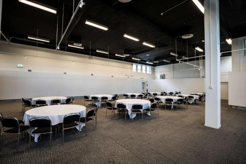 a room with white tables and chairs in it at Scandic Infra City in Upplands-Väsby