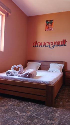 a bed in a bedroom with a sign on the wall at CHAMBRE LA TERRASSE Nosy-be in Hell-Ville