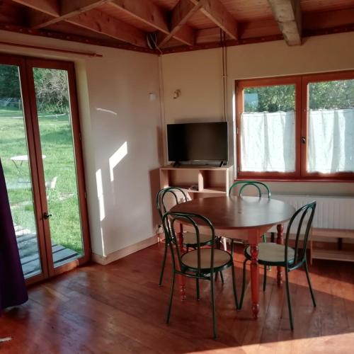 a dining room with a table and chairs and a television at Petit chalet insolite et atypique en Chartreuse in Merlas