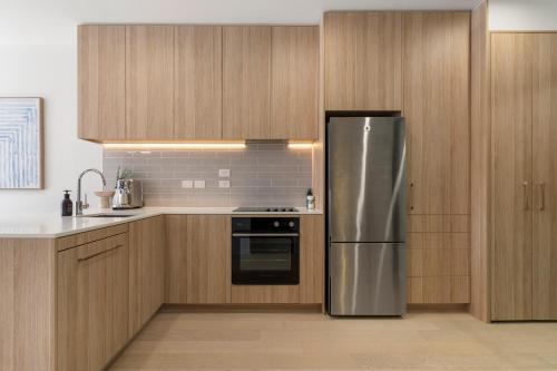 a kitchen with wooden cabinets and a stainless steel refrigerator at The fern - Boutique Mount Albert Townhouse in Auckland