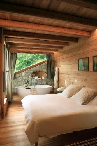 a bedroom with a large bed and a bath tub at Ciasa TRI - Wellness Chalet in Vodo Cadore