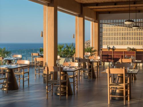 a restaurant with tables and chairs with a view at Lindos Mare, Seaside Hotel in Líndos