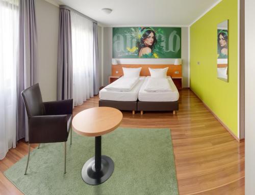 a hotel room with two beds and a table and a chair at attimo Hotel Stuttgart***S in Stuttgart