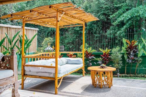 a wooden bed under a wooden pergola with a table at Villa Rosebud in Sukawati