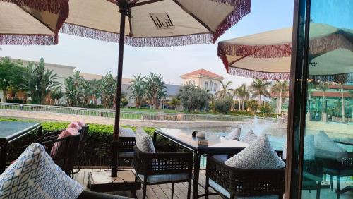 a table and chairs with umbrellas in front of a pool at 3BR furnished apartment in Madinaty B1 شقة مفروشة 3 غرف نوم في مدينتي in Madinaty