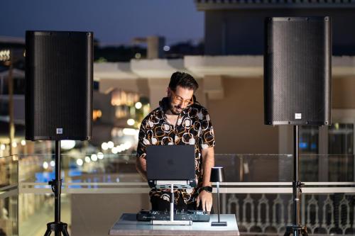 a man working on a laptop on a table with speakers at Porto Planos Beach Hotel in Tsilivi