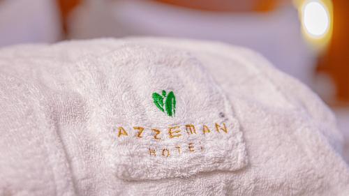 a white towel with a green leaf on it at Azzeman Hotel in Addis Ababa
