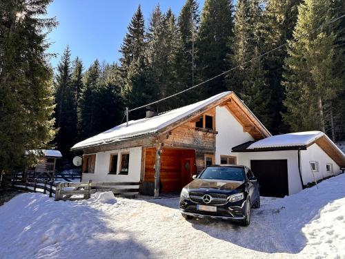 a car parked in front of a house in the snow at Fleissner Hütte in Innerkrems