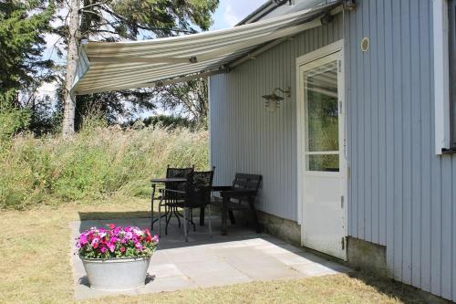 a porch of a house with a table and flowers at Gäststuga på landsbyggden utanför L Alstad in Trelleborg