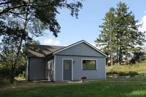 a gray shed with a door in a yard at Gäststuga på landsbyggden utanför L Alstad in Trelleborg