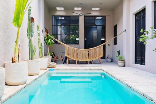 a hammock in the backyard of a house with a swimming pool at Casa Lirios - Luxury Colonial Villa in Mérida Centro with Pool in Mérida