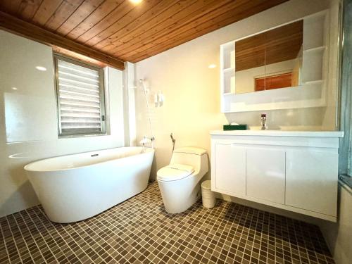 a bathroom with a tub and a toilet and a sink at Ivy Motel in Chiayi City