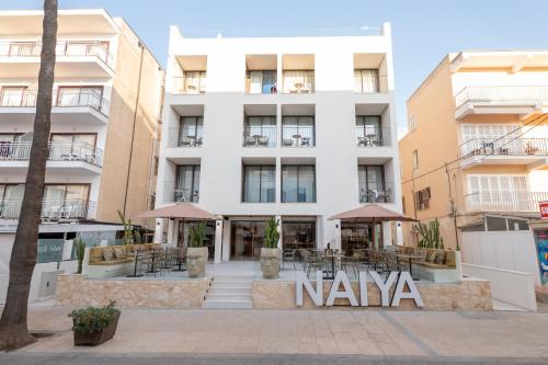 a large white building with tables and umbrellas at Marins Naiya Boutique Hotel in Cala Bona