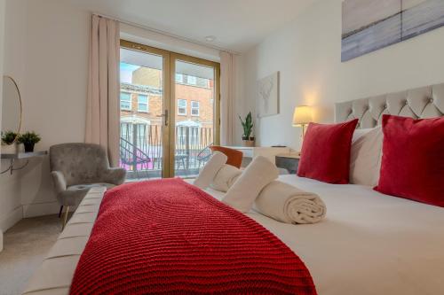 a bedroom with a large bed with red and white pillows at Luxe London Retreat in London