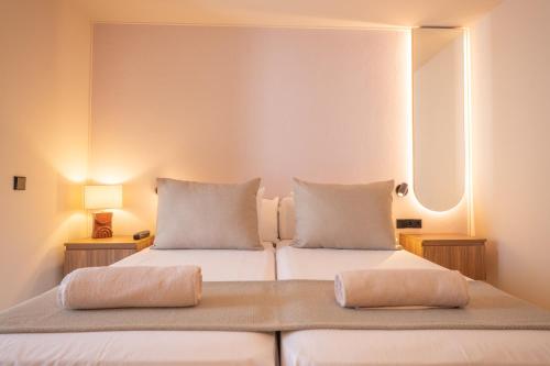 a bedroom with two beds with pillows and a mirror at Marins Naiya Boutique Hotel in Cala Bona