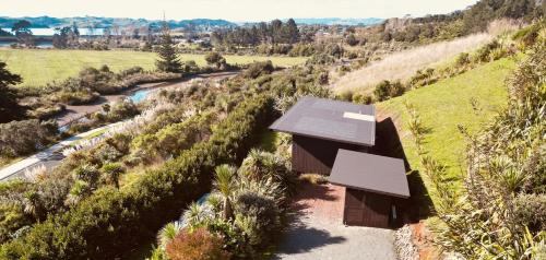 a small house on a hill with a road at Whare Tatū in Raglan
