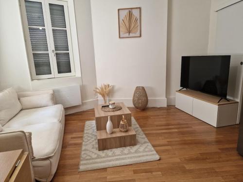 a living room with a couch and a tv at Appartement T2 - Centre-ville in Saint-Pourçain-sur-Sioule