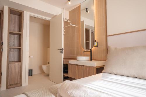 a bedroom with a bed and a bathroom with a sink at Marins Naiya Boutique Hotel in Cala Bona