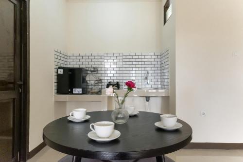 a black table with cups and a vase with a flower at Salma Syariah by TwoSpaces, Bogor in Jakarta