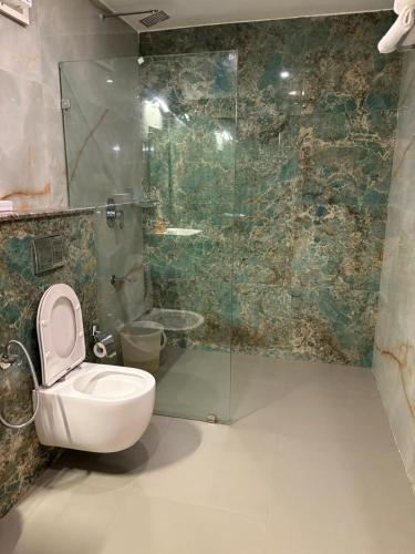 a bathroom with a toilet and a glass shower at Symphony in Ooty