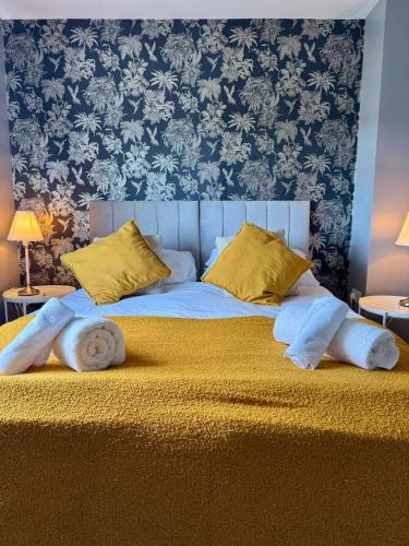 a large bed with yellow pillows and a blue wall at Home in between Bath and Bristol - Sleeps 9 guests in Keynsham