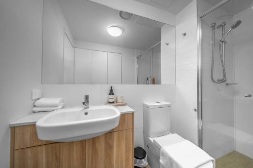 a white bathroom with a sink and a shower at 2BR Apt in Proximity Hamilton with Carpark in Brisbane