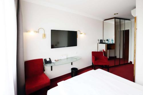 a hotel room with a red chair and a mirror at Best Western Plus Hotel St. Raphael in Hamburg