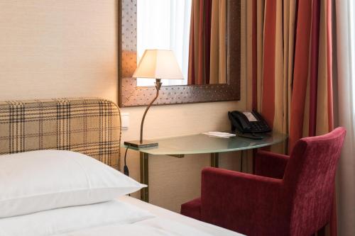 a hotel room with a bed and a table and a phone at Best Western Plus Hotel St. Raphael in Hamburg