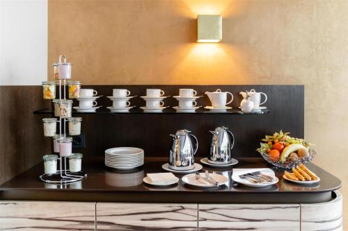 a table with plates and cups and a bowl of fruit at Best Western Plus Hotel St. Raphael in Hamburg