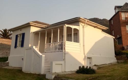 a white house with a porch and a fence at Boulders Beach Hotel, Cafe and Curio shop in Simonʼs Town