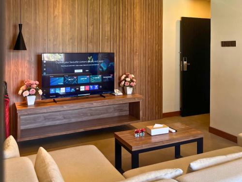 a living room with a tv and a couch and a table at Kana Suites Jimbaran By Fays Hospitality in Nusa Dua
