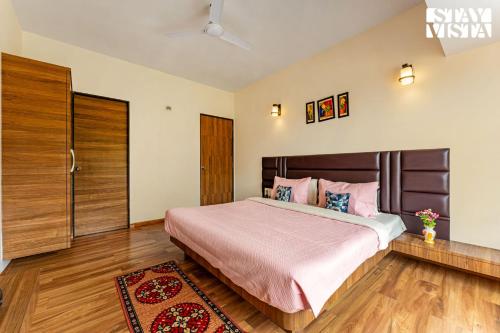 a bedroom with a large bed with pink pillows at Blisswood Villa by VEO - Part of StayVista in Trimbak