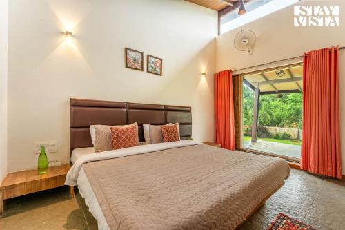 a bedroom with a bed and a large window at Blisswood Villa by VEO - Part of StayVista in Trimbak