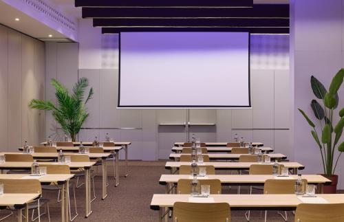 an empty classroom with tables and a projection screen at ME Barcelona in Barcelona