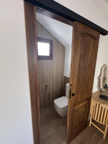 a bathroom with a toilet and a wooden door at Corona beach in Daimuz
