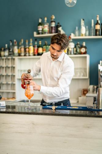a man standing at a counter preparing a drink at HOTEL CONTI in San Mauro a Mare