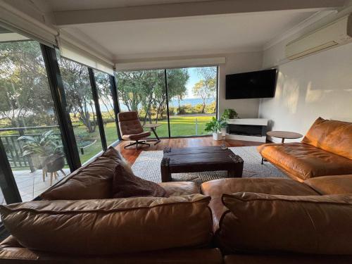 a living room with a brown couch and a chair at 5@CapeView, beachfront Geographe Bay in Busselton