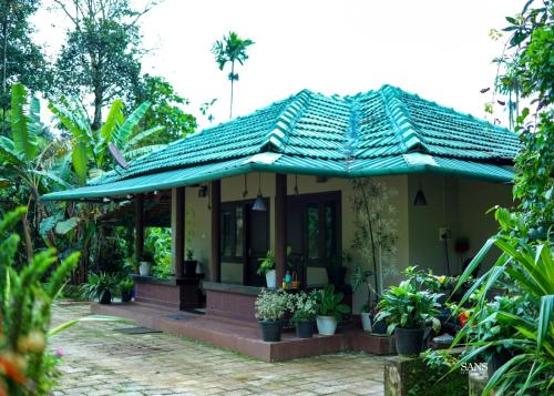 una pequeña casa amarilla con techo verde en Paddy Land, en Wayanad
