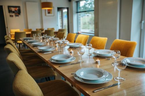 a long wooden table with plates and wine glasses at Le Bonheur de la Cascade 24 pers - Malmedy, wellness, jardin, confort in Malmedy