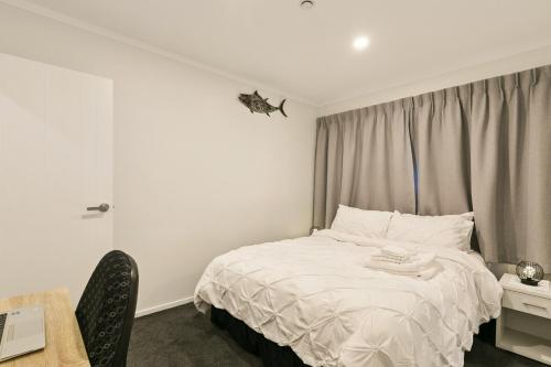 a bedroom with a white bed with a butterfly on the wall at Modern 1 Bed Smart Flat in Upper Hutt with Full Kitchen, Parking - 5 minutes to Brewtown in Upper Hutt