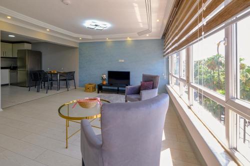 ein Wohnzimmer mit Stühlen und einem Tisch und Fenstern in der Unterkunft Maxihomes Near Hadrian Gate & Beach, with Sea Views in Antalya