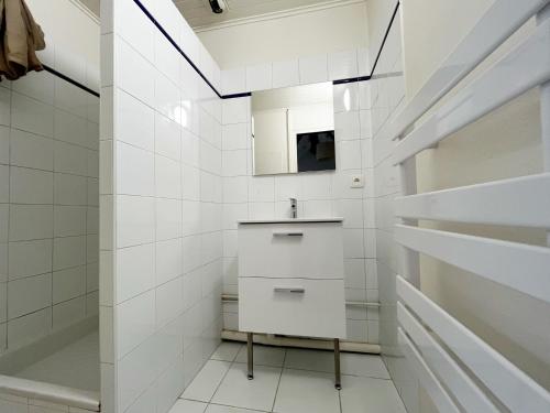 Un baño blanco con lavabo y espejo. en POLKE - appartement 3 personnes - check in h24 - wifi, en Lyon