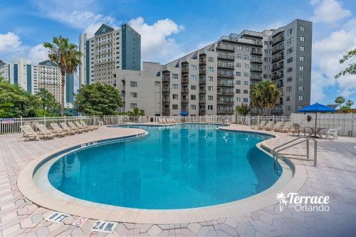 a swimming pool with chairs and buildings in the background at Volcano View 2 Bed 2 Bath Condo with Balcony in Orlando
