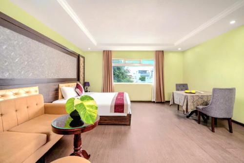 a hotel room with a bed and a couch and a table at Me Q Beach Hotel & Apartment in Da Nang