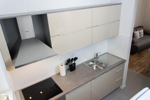 a kitchen with white cabinets and a sink at Apartment Gamma with hydromassage mini pool near Split in Žrnovnica