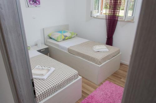 two twin beds in a small room with a pink rug at Apartment Gamma with hydromassage mini pool near Split in Žrnovnica