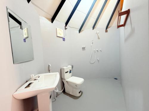 a white bathroom with a sink and a toilet at Tribal Village in Trincomalee